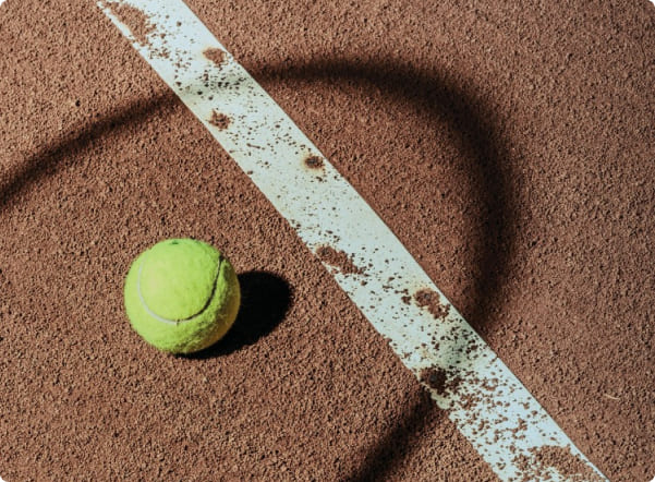 Tennis player serving ball on outdoor court during match